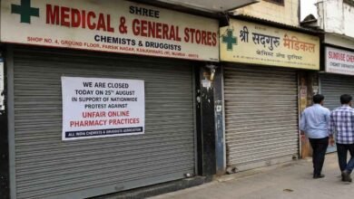 Closed medical shops with protest notice displayed on shutters during a nationwide pharmacy protest in a busy street area.