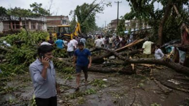 People gather on a damaged road in Uttar Pradesh after a powerful storm and heavy rainfall killed 11 people and caused major destruction across affected areas.